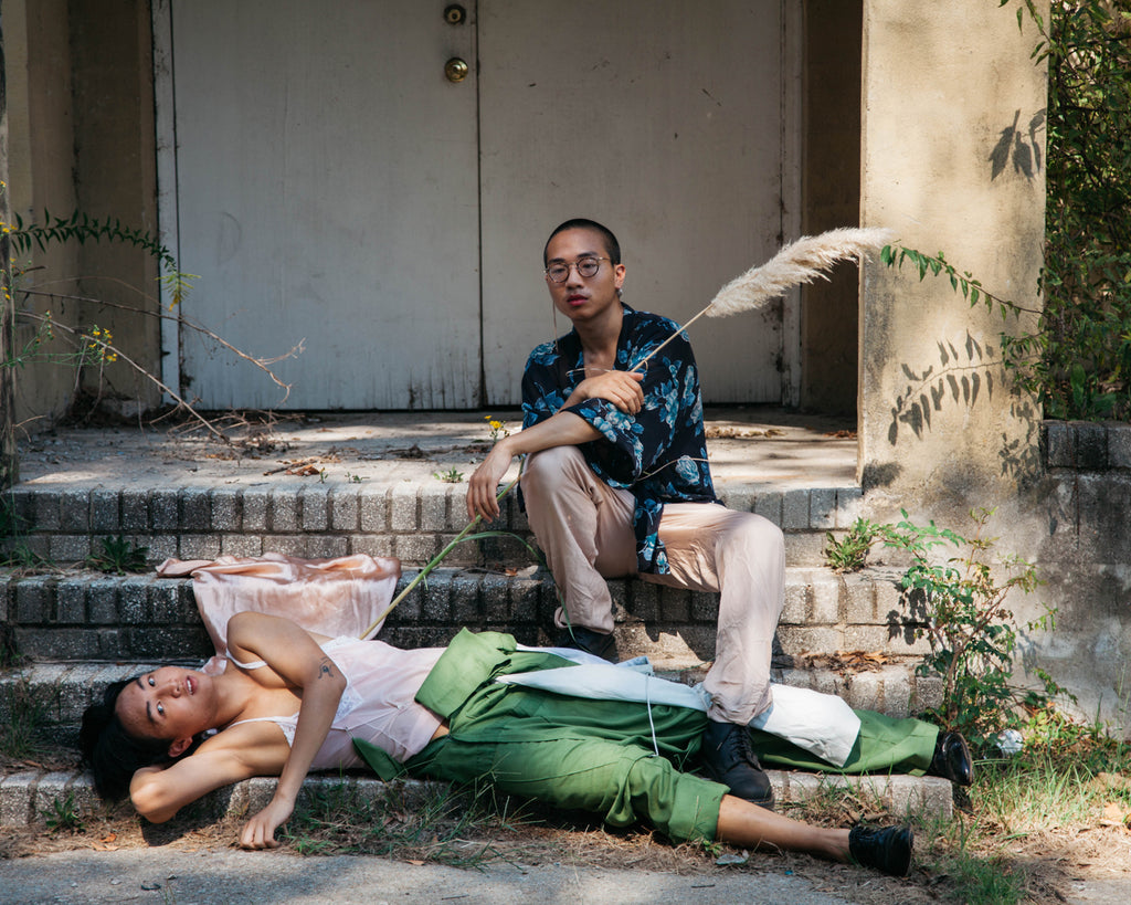 duo posing, laying on the steps of an old building.