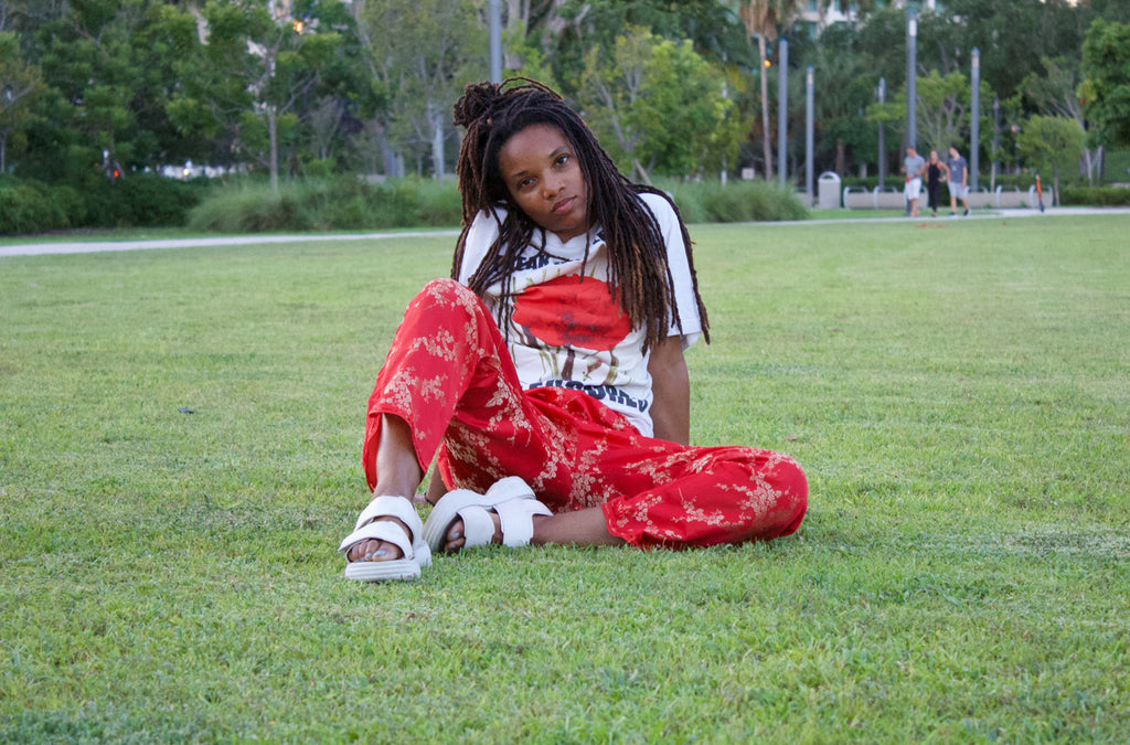 a person with red pants sitting in the grass.