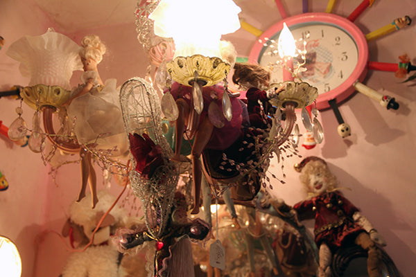 chandelier with dolls and colorful clock in the background.