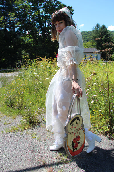 person walking with matryoshka doll bag.