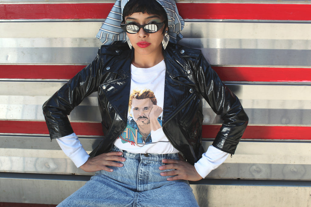 model in front of diner in leather jacket, jeans and sunglasses.