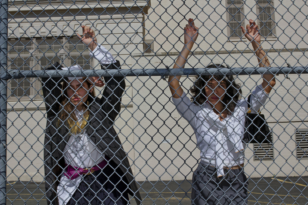 models posing through chain link fence.