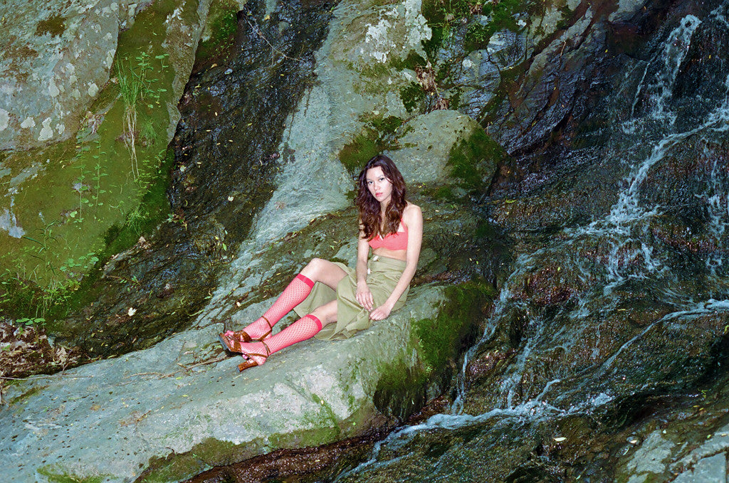 model seated next to waterfall.