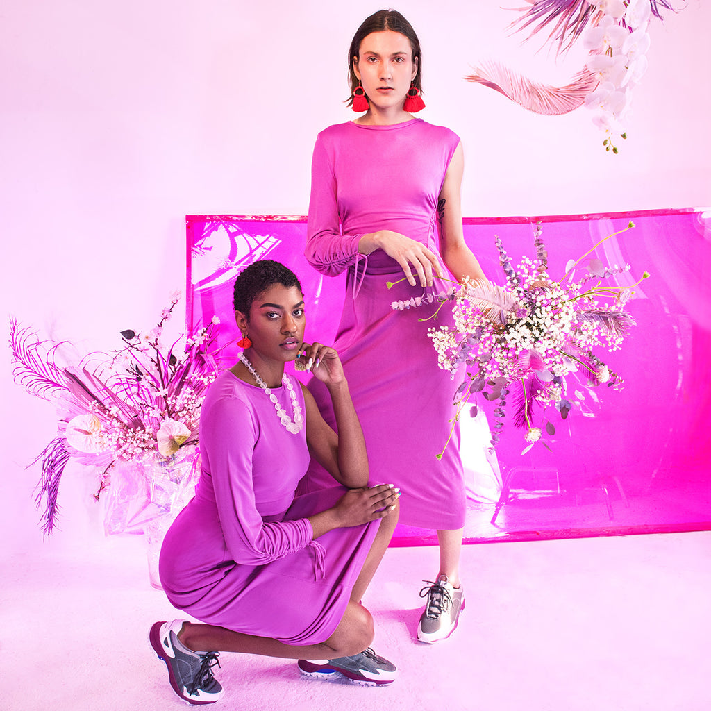 two models posing one squatting one standing in tonal looks with tonal backdrop. 