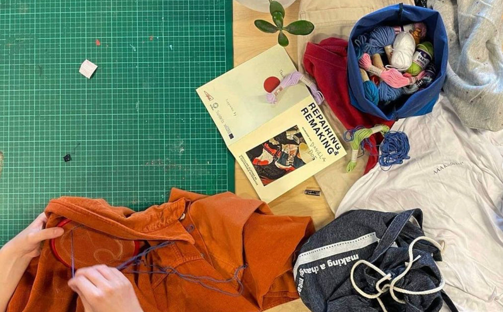 screenshot of artists desk with a book title that reads repairing remaking