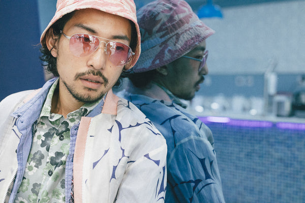 model detail portrait featuring sunglasses and bucket hat in reflection.