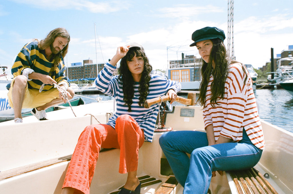models in striped attire in sailboat at docks.
