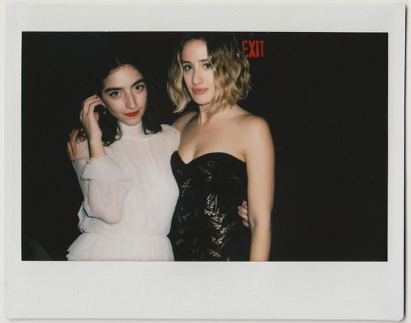 two employees posing, one touching hair with right hand, the other one slightly smiling – polaroid style.