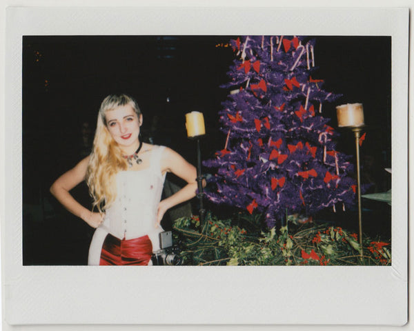 employee posing next to a purple christmas tree - polaroid style. 