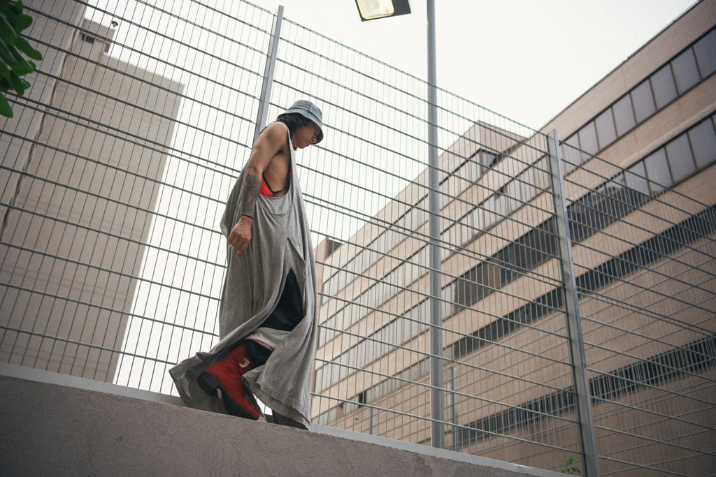 rao walking on cement barrier in sleeveless knit dress and bucket hat.