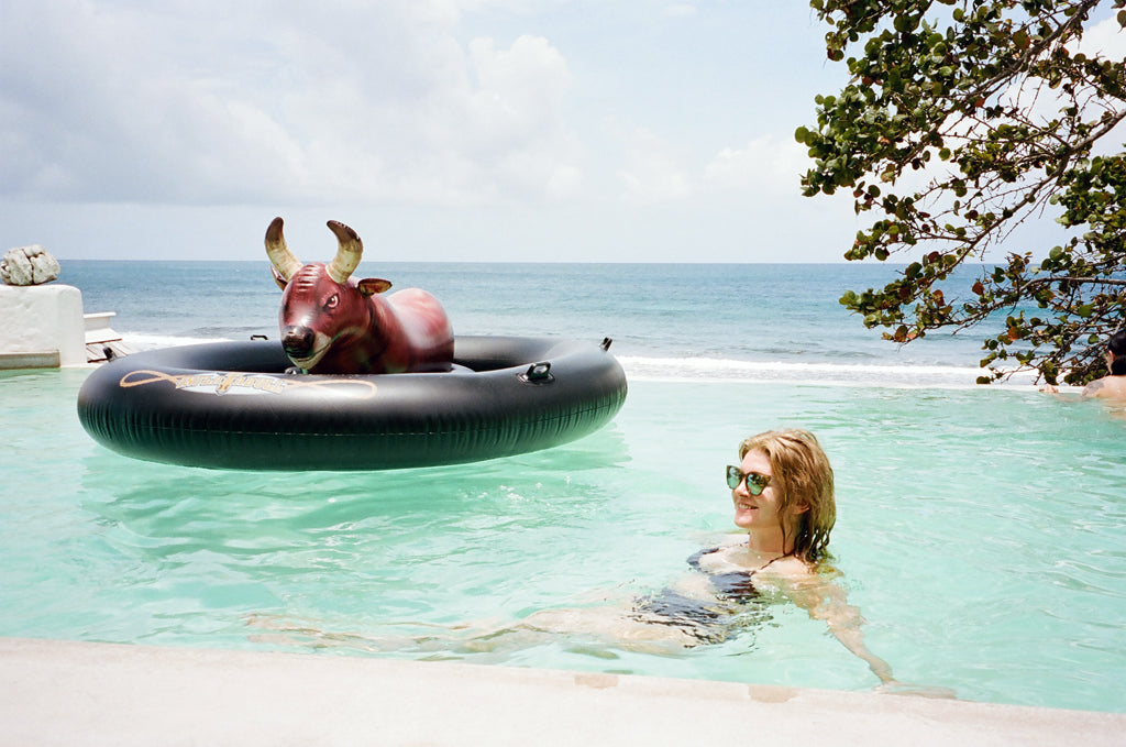 a person sitting in a pool with an inflatable bull.