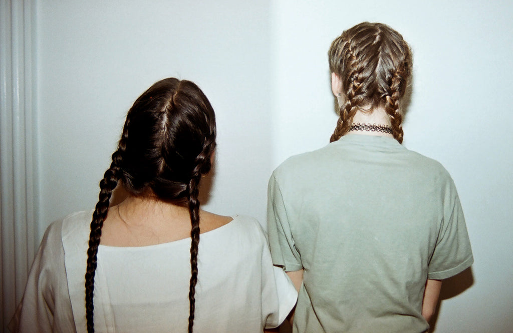 duo with braided hair standing next to each other.