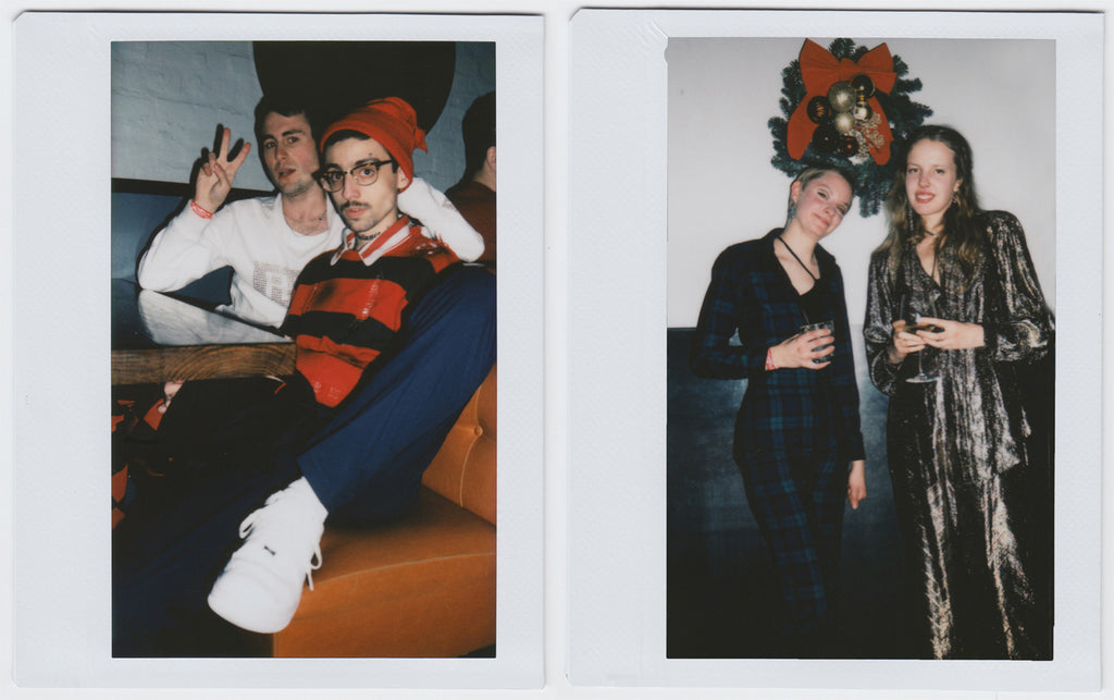 first image: two people posing, one with foot on chair, the other making 'peace and love' gesture. second image: duo posing, christmas ornament in the back, full body shot - polaroid style.