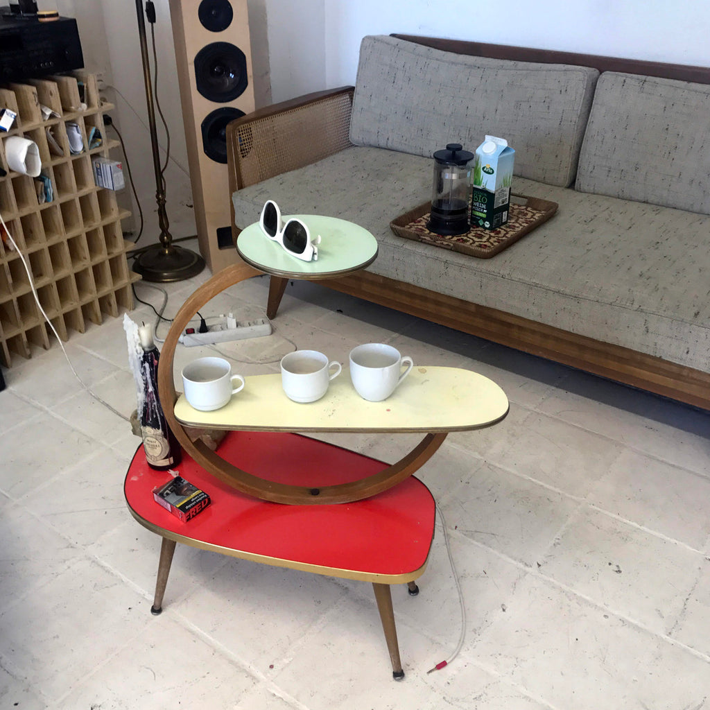 a coffee table in a living room with coffee cups and cigarettes on it.