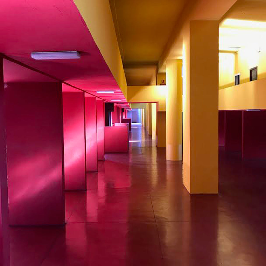 a hallway with red and yellow walls and pillars.