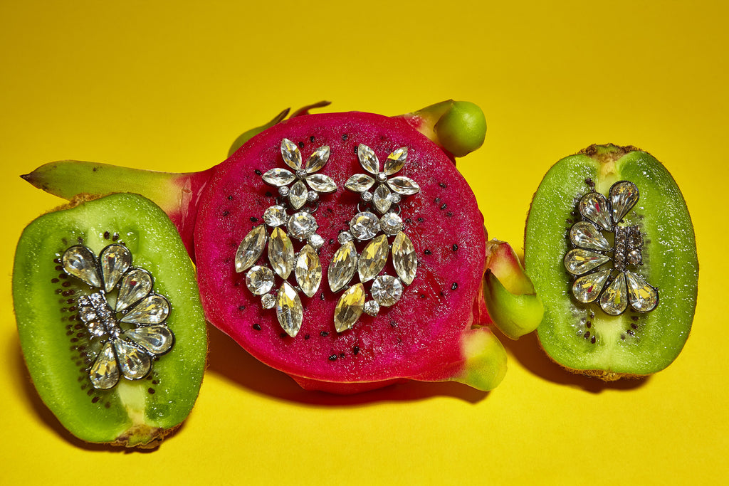still life featuring kiwis and dragon fruit with jewelry.