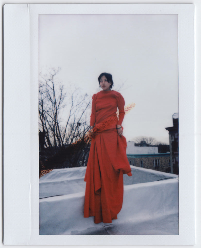 indra on their roof in long red dress.