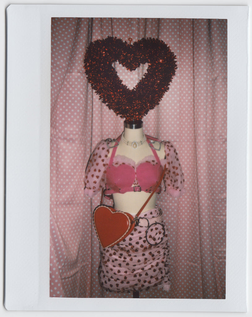 tinsel heart on top of mannequin in heart print two piece and heart shaped bag.