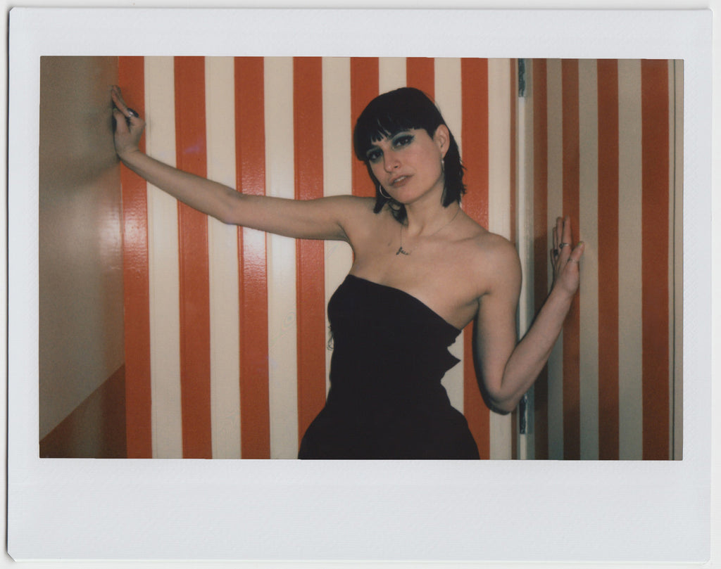 person posing with hands against the wall, looking directly at camera - polaroid style.
