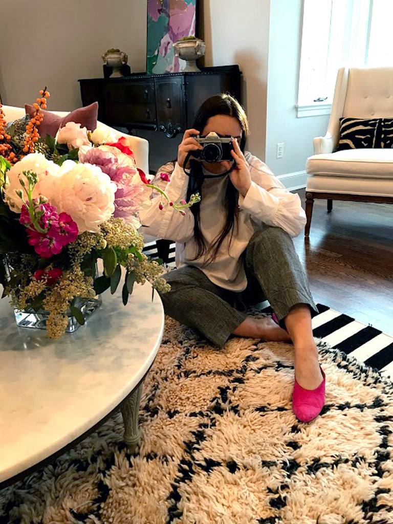 delcey taking a picture of herself in a living room with flowers.