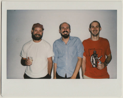 kyle and employees posing to the camera, smiling - polaroid style.