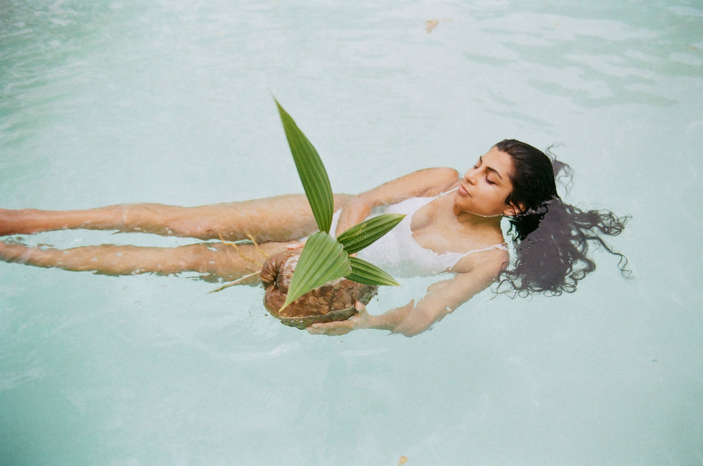a person laying in a pool with a plant in their hand.