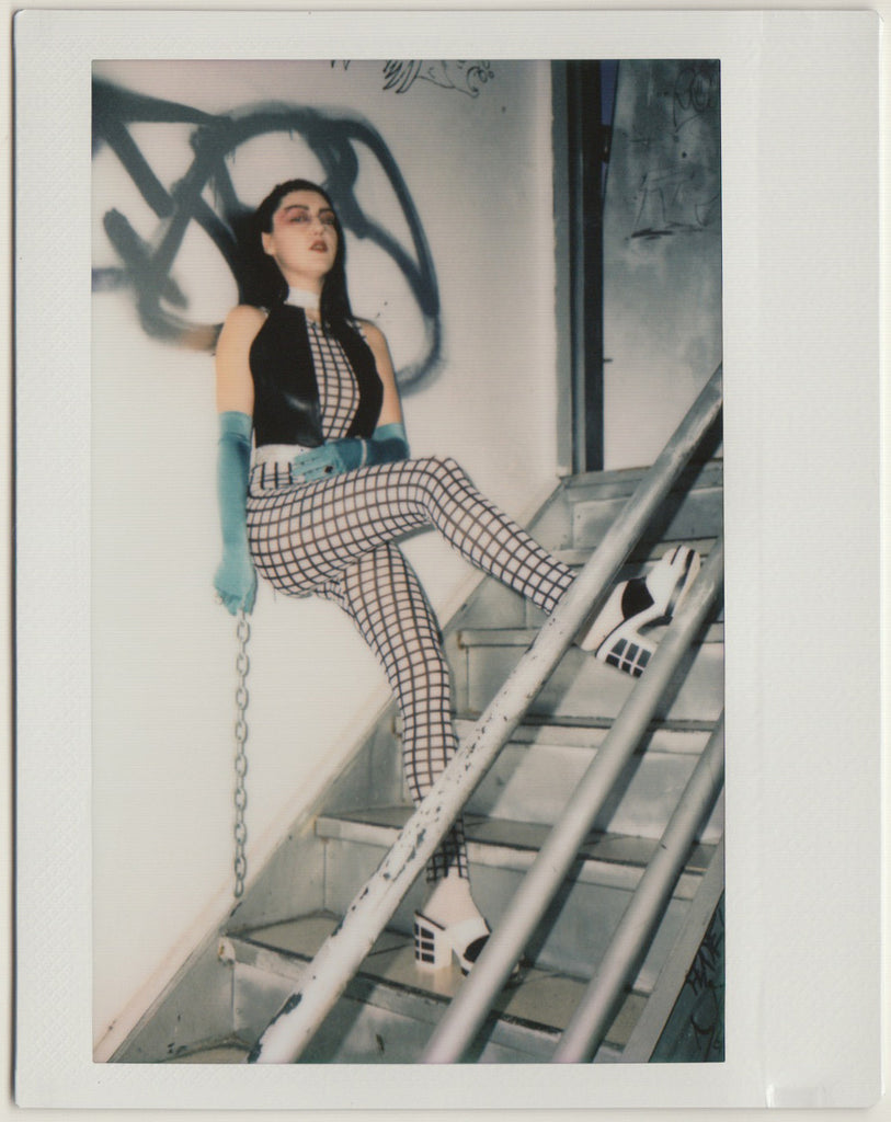 nina in stairwell in geometric look holding a chain.