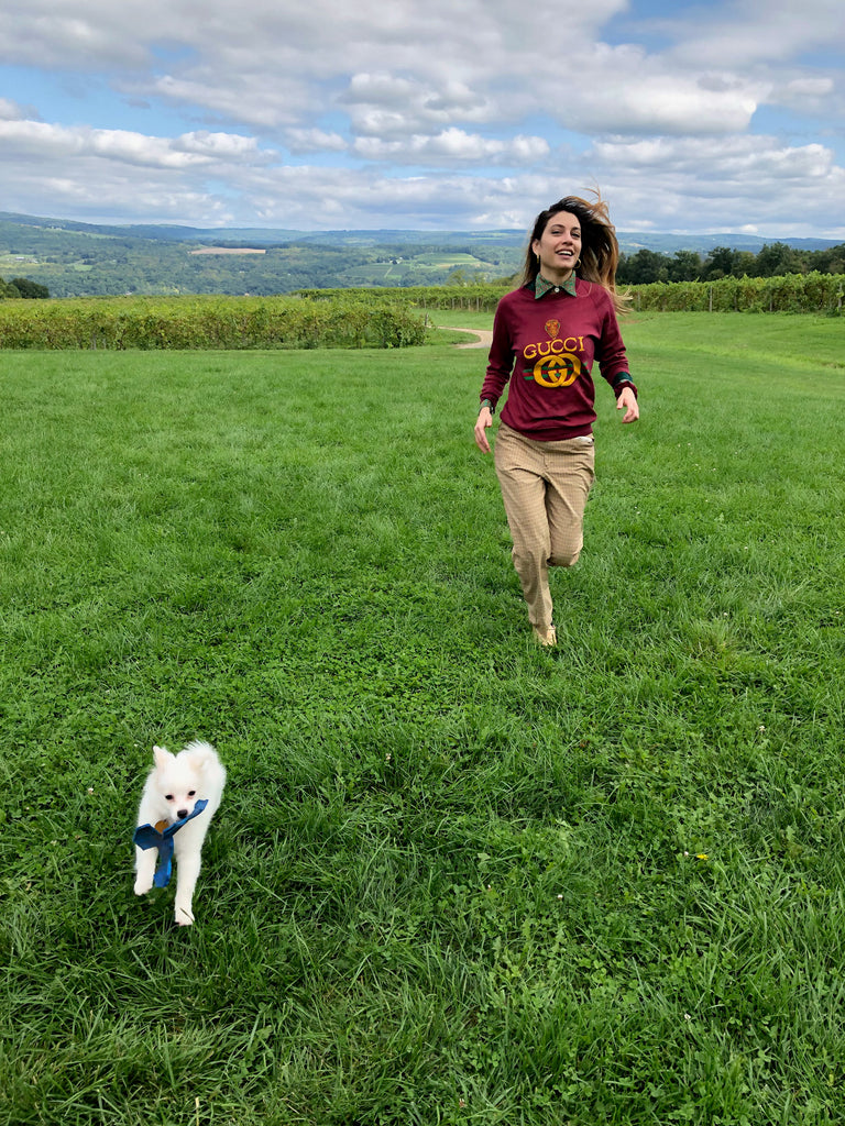 a person running in the fields with a white dog.