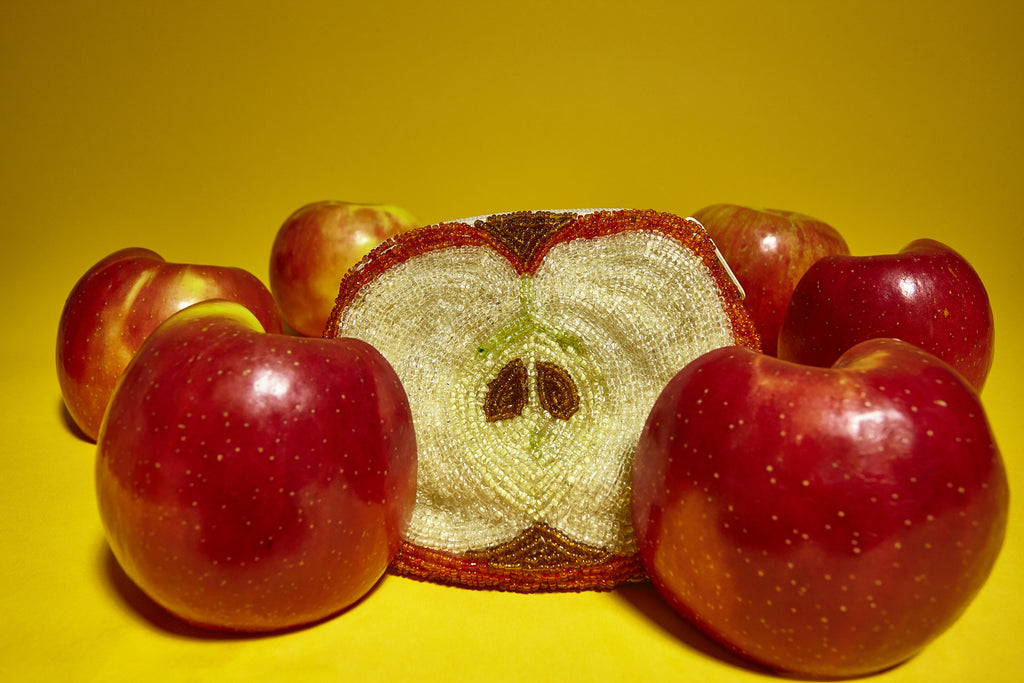 still life featuring apples and beaded apple coin purse.