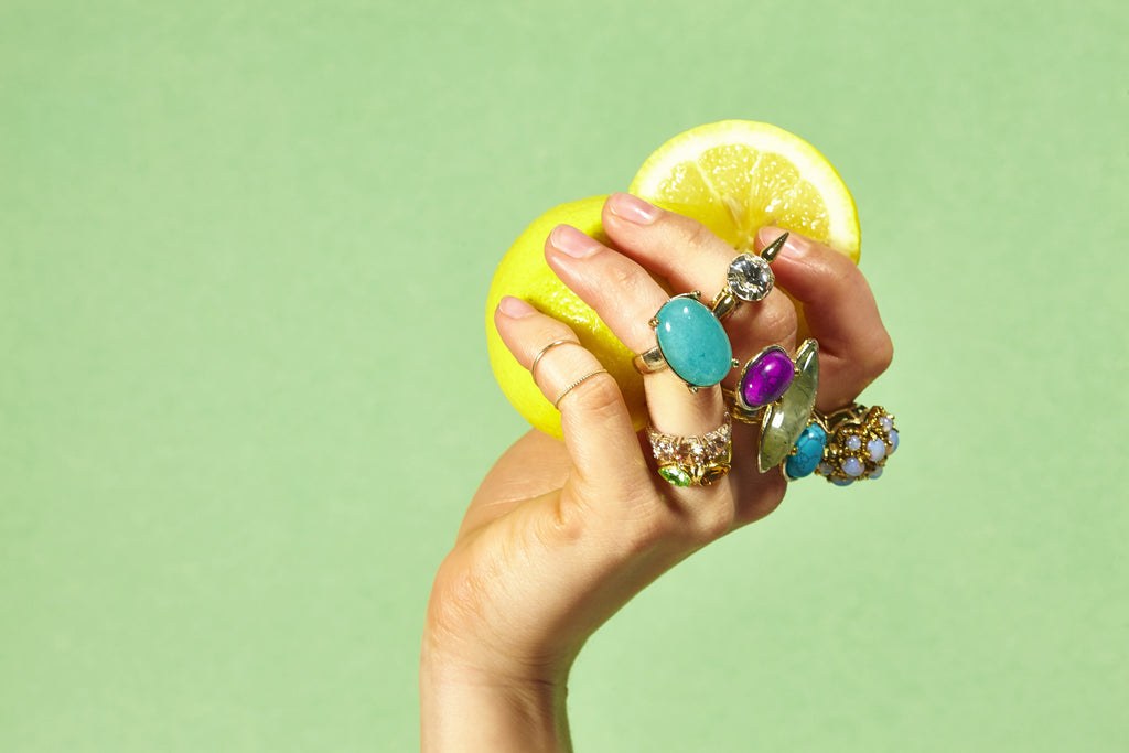 models hand holding a lemon and wearing rings.