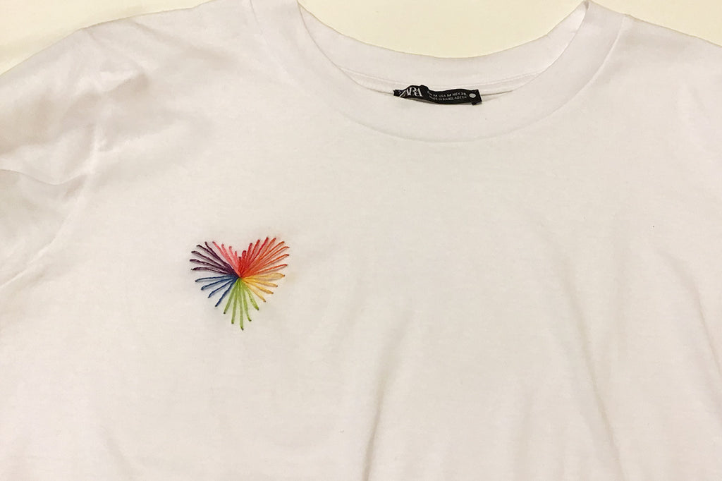 Heart strings stitched on white t-shirt in rainbow threads