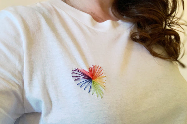 Rainbow threads stitched on a white t-shirt in a heart design