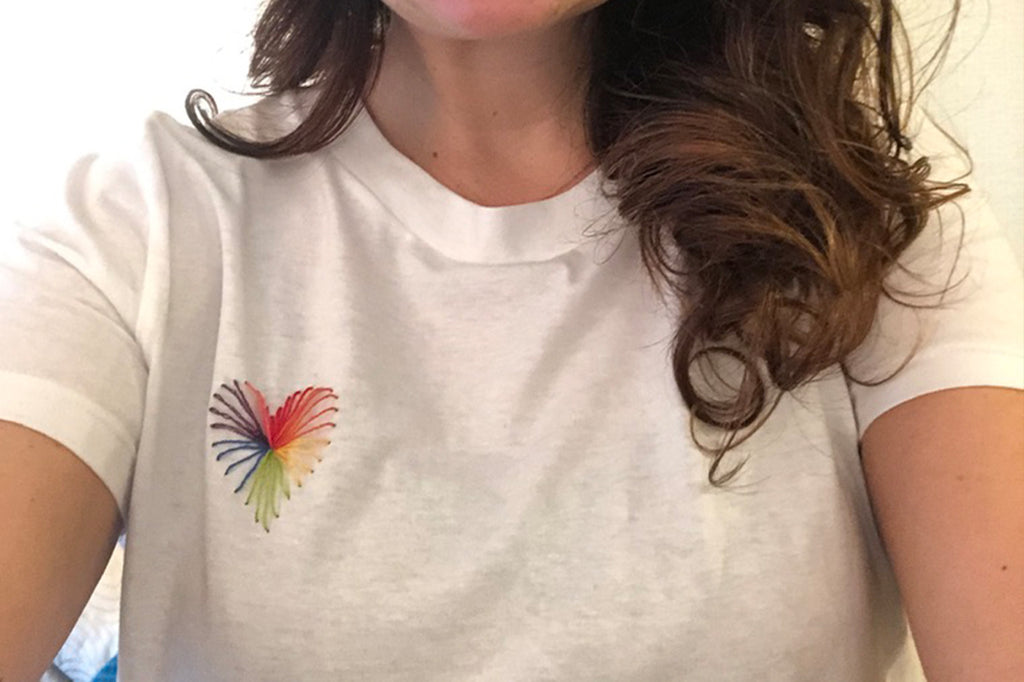 Heart strings stitched on white t-shirt in rainbow thread worn by a woman