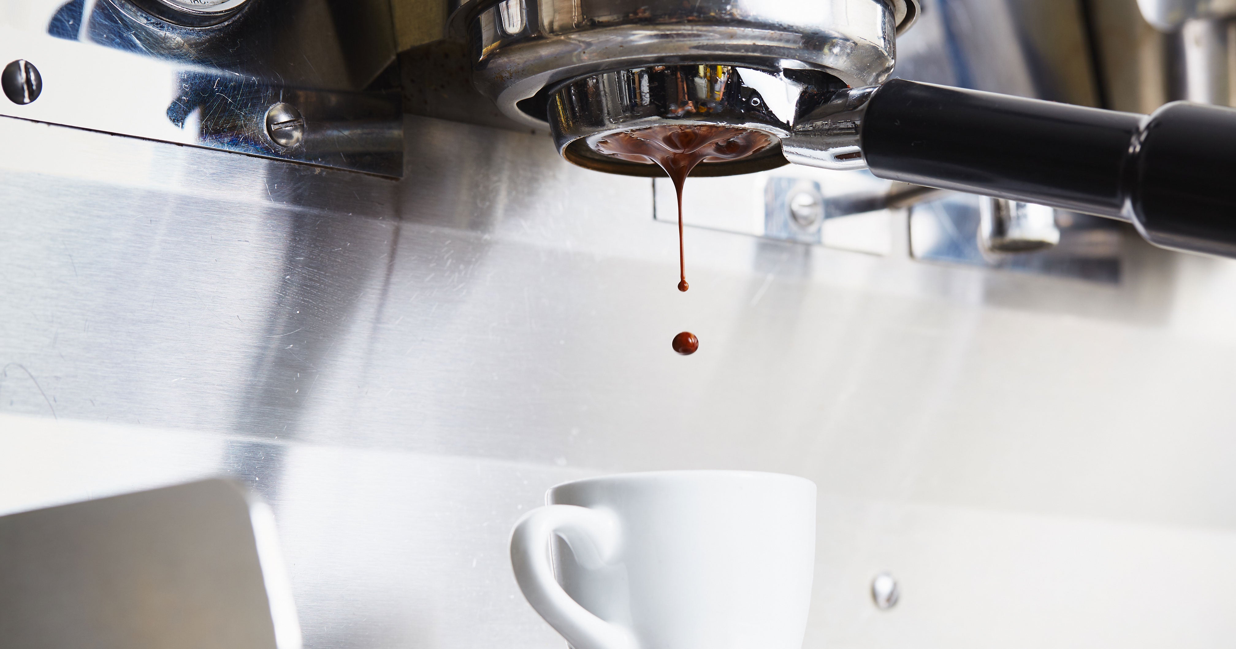 espresso being extracted out of a bottomless portafilter into a white cup