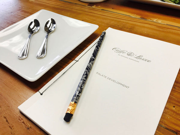 a caffe luxxe palate development workbook next to a square plate with two spoons