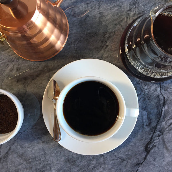 cup of coffee from above with a kettle and a decanter behind it