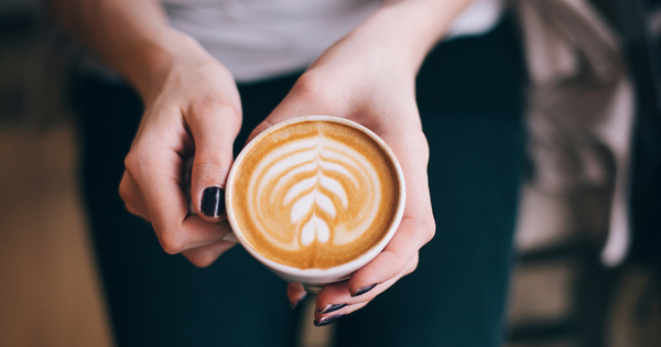 Person holding a cappuccino with latte art on it.