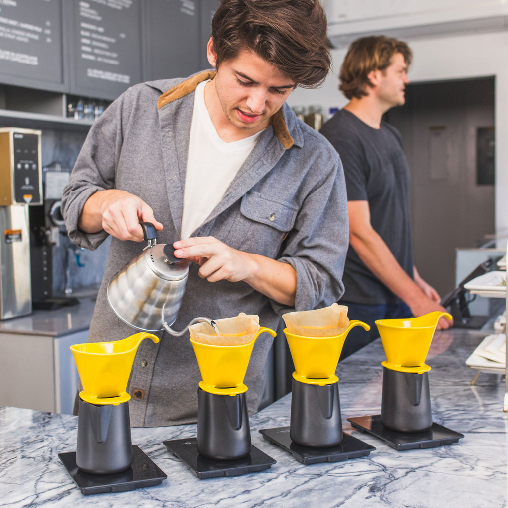 man pouring water into pour over coffee maker