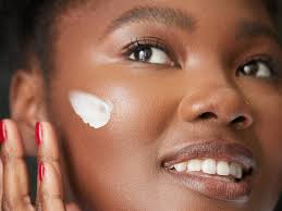 woman of color applying sunscreen on face