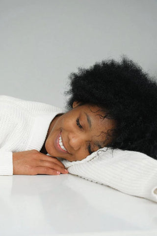 petty black woman laying in bed smiling