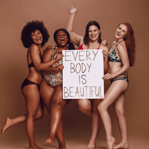 Beautiful ethnic women in bikinis holding a sign reminding you to love and embrace your skin, Sweet Surrender Blog: Embrace your skin through self care