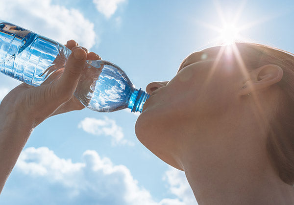 Woman drinking a bottle of water in the sun.