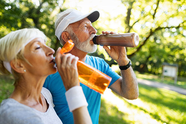 Older couple drinking from water bottles.
