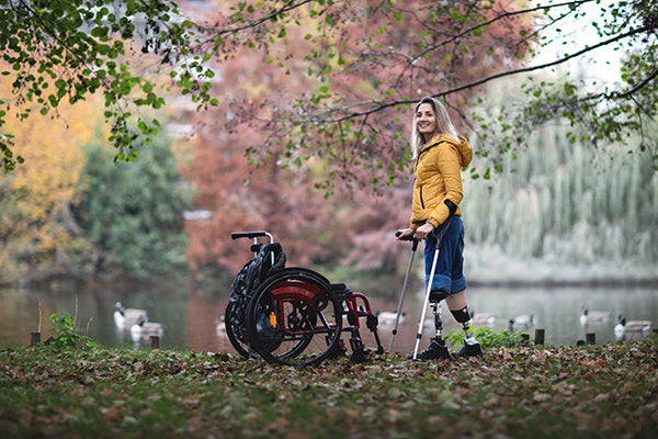 Girl with prosthetic legs in park with wheelchair