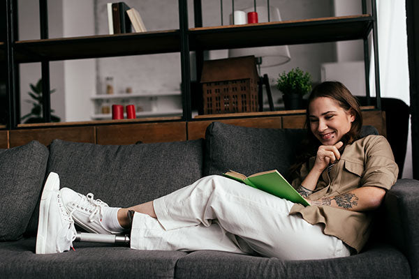 Woman with limb loss sitting on a couch.