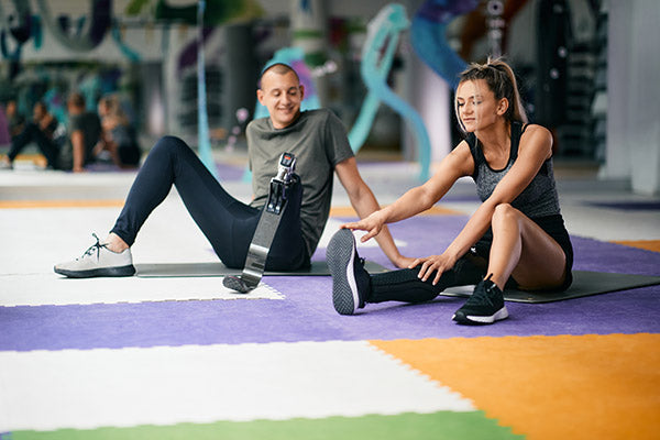 Man and woman sitting on exercise mat.