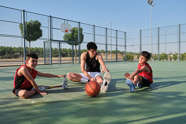 Three young men stretching on a basketball court.