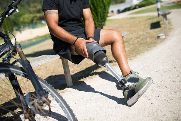 Individual with limb loss sitting on a bench in pain.