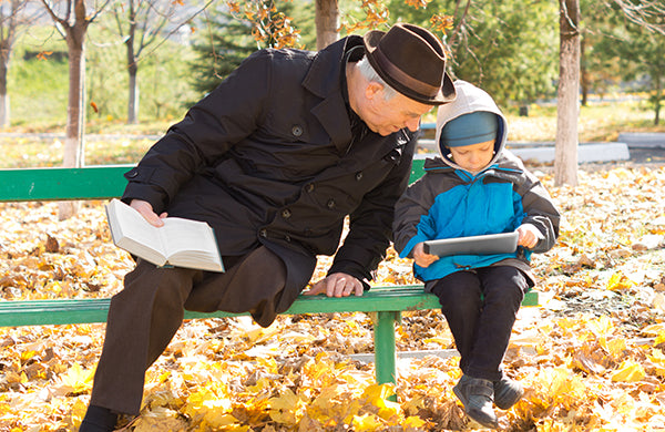 Older man sitting on a park bench with his grandson.
