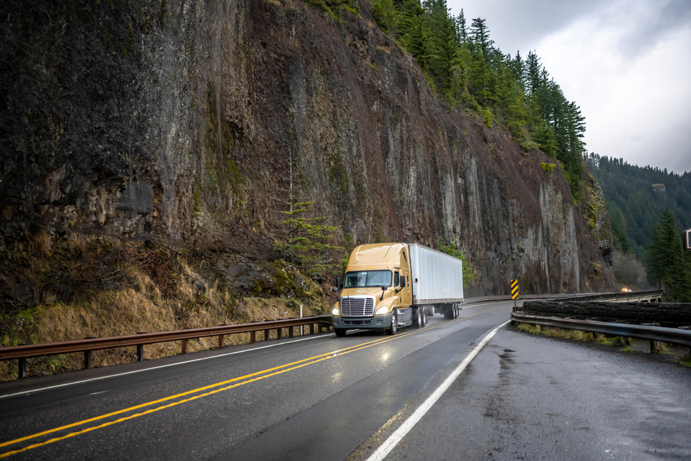 Freight truck driving forest mountain highway